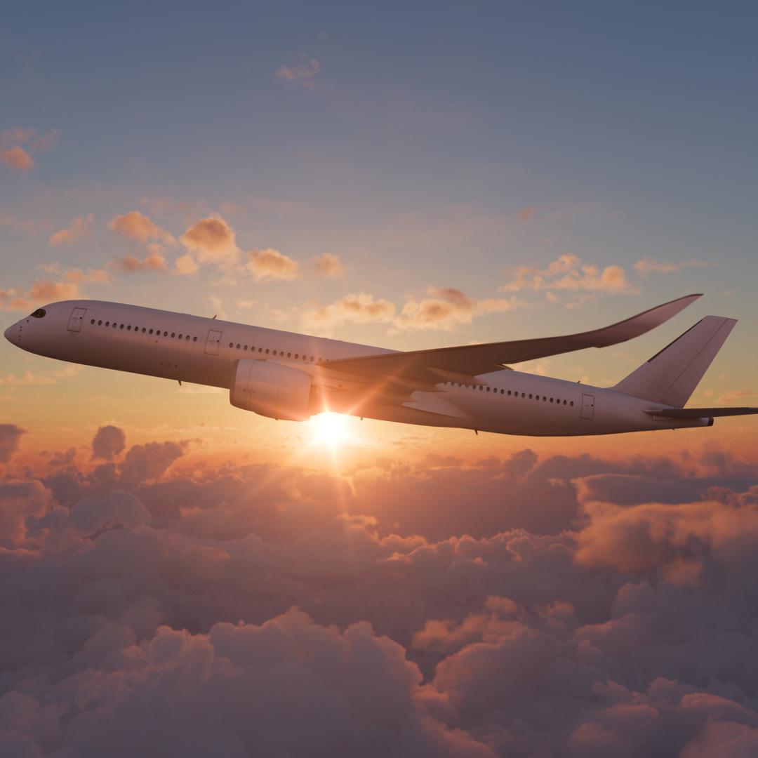 Ein Flugzeug fliegt bei Sonnenuntergang hoch über dichten, orangefarbenen Wolken.