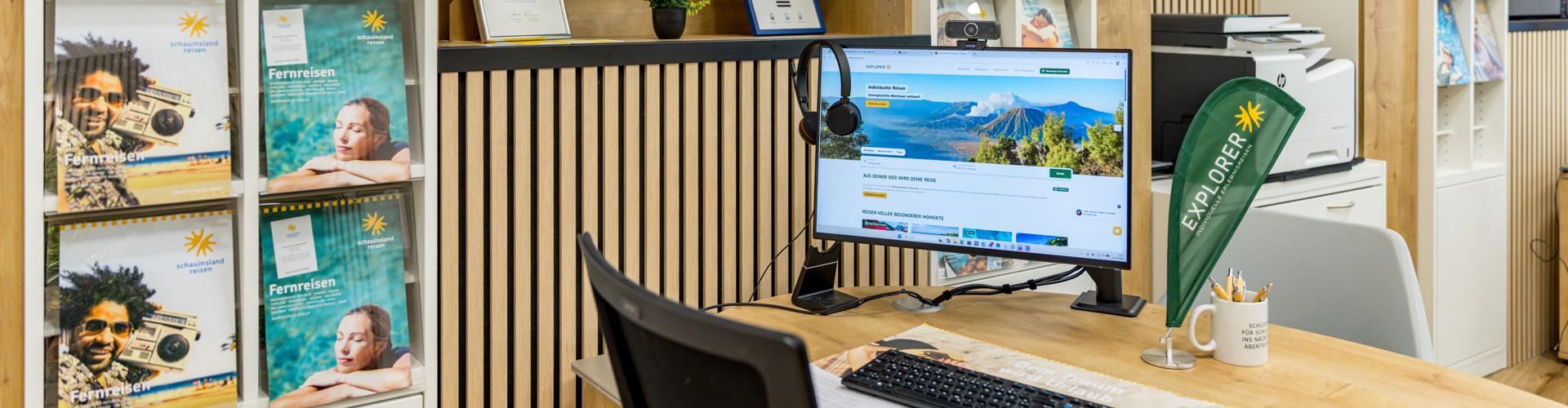 Moderner Empfangstresen mit Computer, Prospekten und Dekoration in einem hellen Reisebüro.