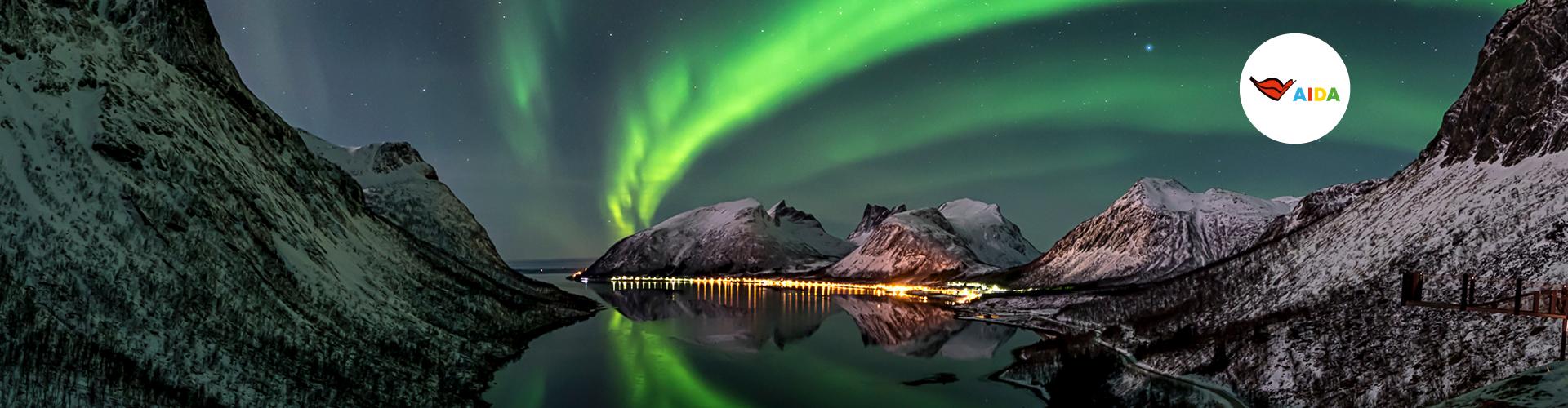 Nordlicht über verschneiten Bergen und ruhigem Fjord, ideal für Winterurlaub und Naturerlebnis.