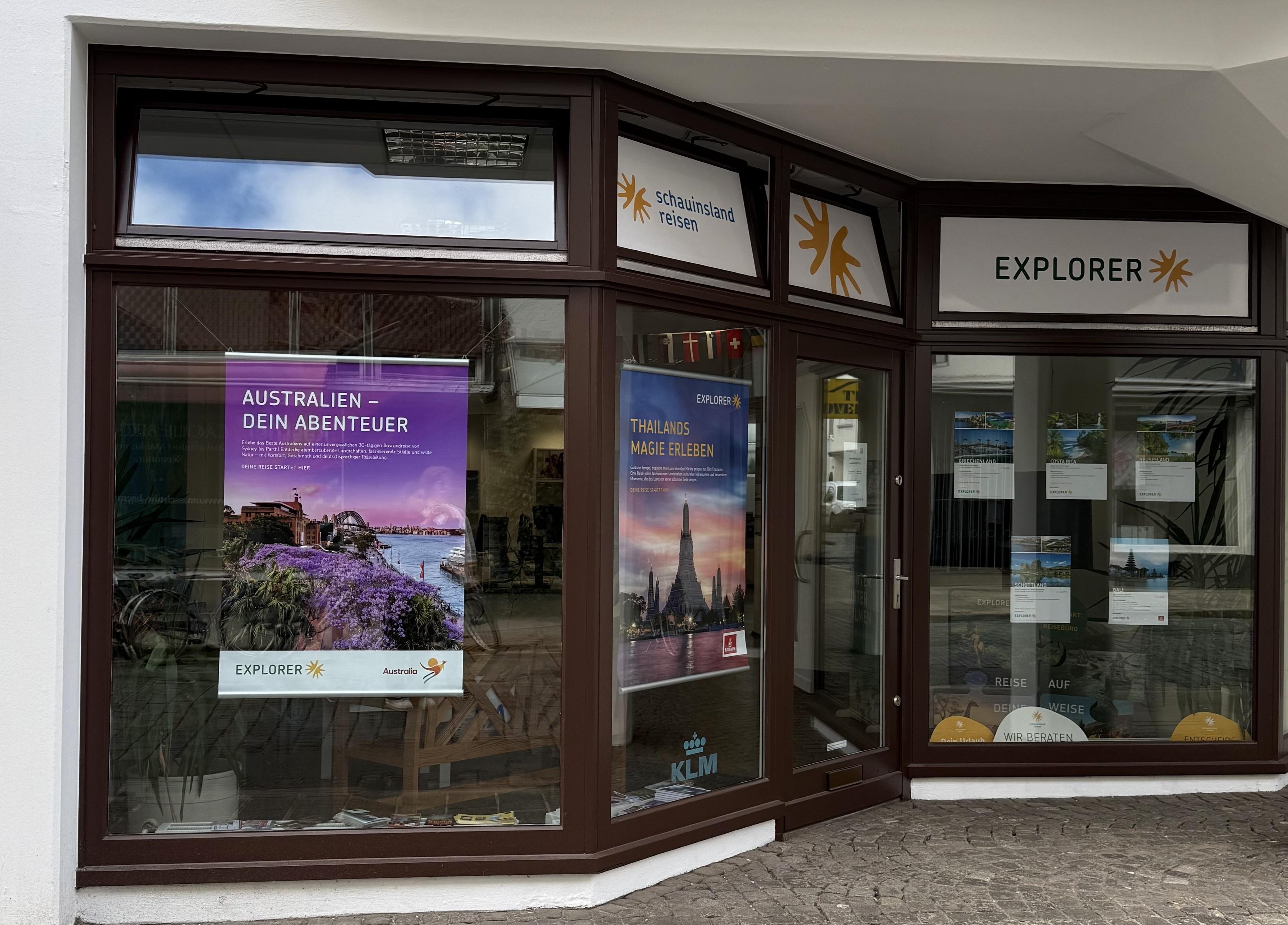 Reisebüro mit großen Fenstern, detailreichen Reiseplakaten und moderner, klarer Beschilderung.