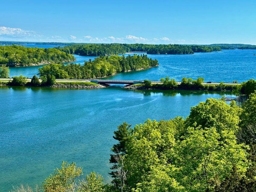 Idyllische Seenlandschaft mit grünen Inseln und einer kleinen Brücke, ideal für einen ruhigen Urlaub.