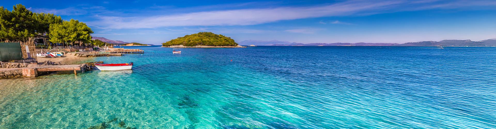 Klares türkisfarbenes Meer an sonniger Küste mit Inseln, ideal für Urlaub und Erholung am Hotelstrand.